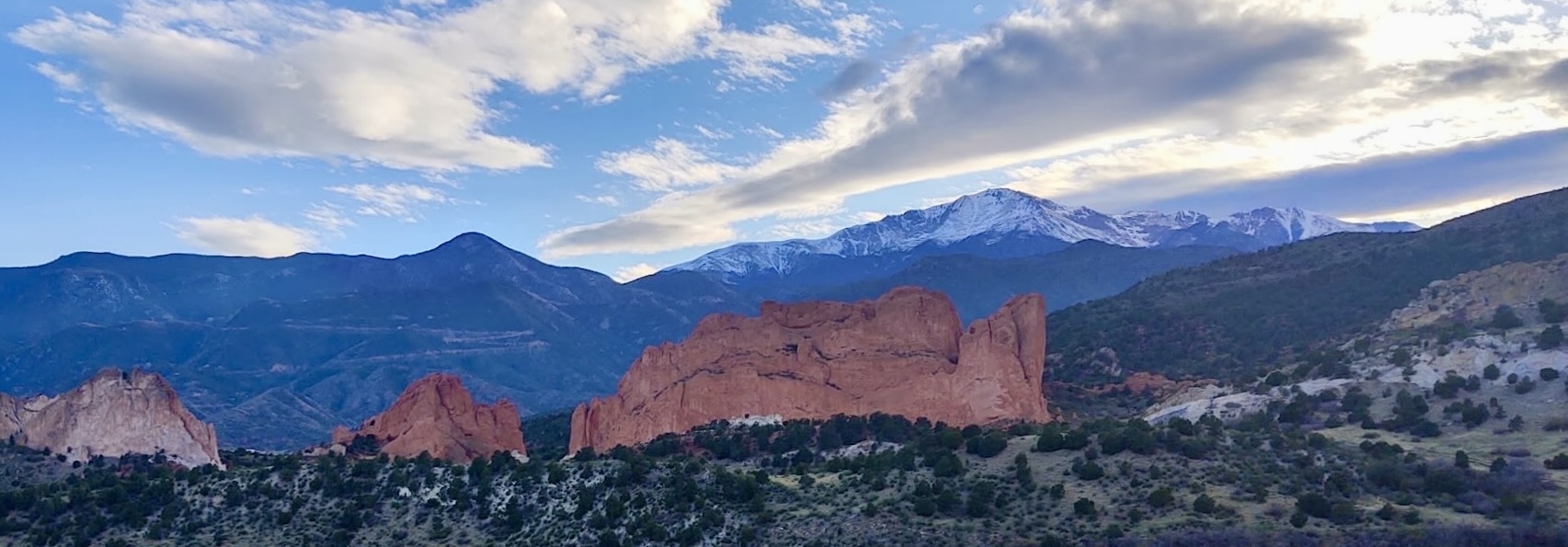 Scenic view of Garden of the Gods with red rock formations and a backdrop of snow-capped mountains